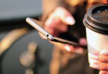 Person drikker kaffe med telefon i hånden