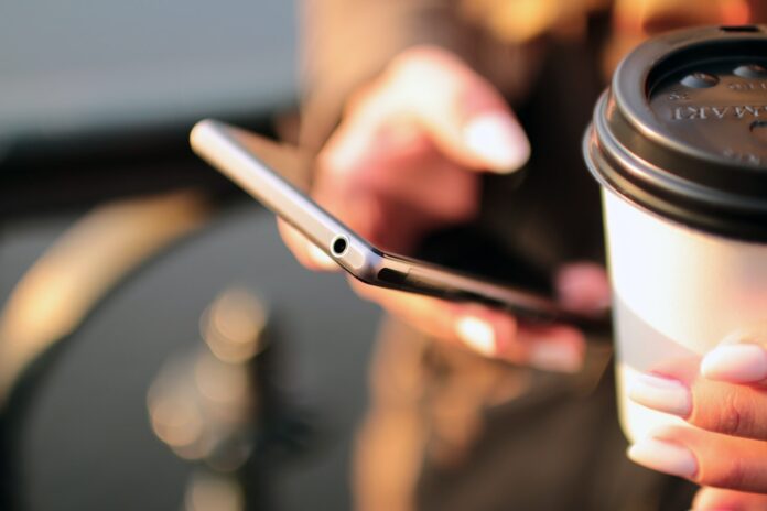 Person drikker kaffe med telefon i hånden Person drikker kaffe med telefon i hånden